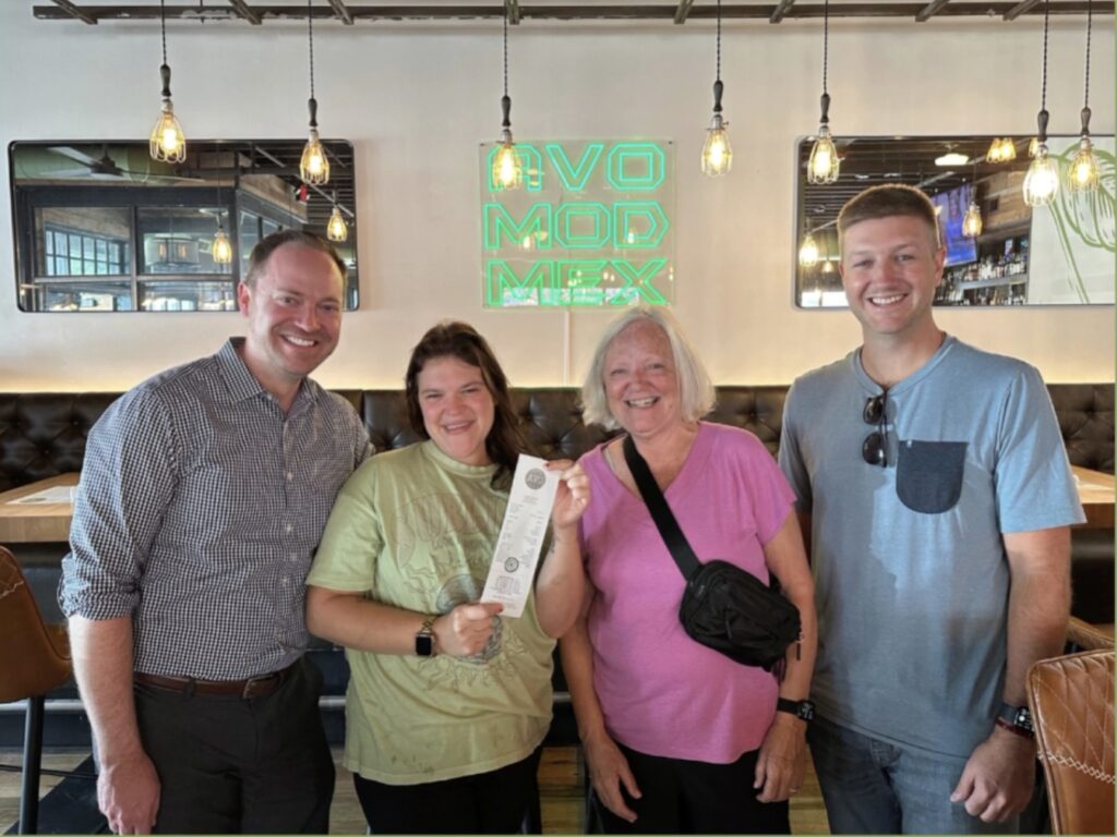 Four people holding a receipt with a $1,000 tip