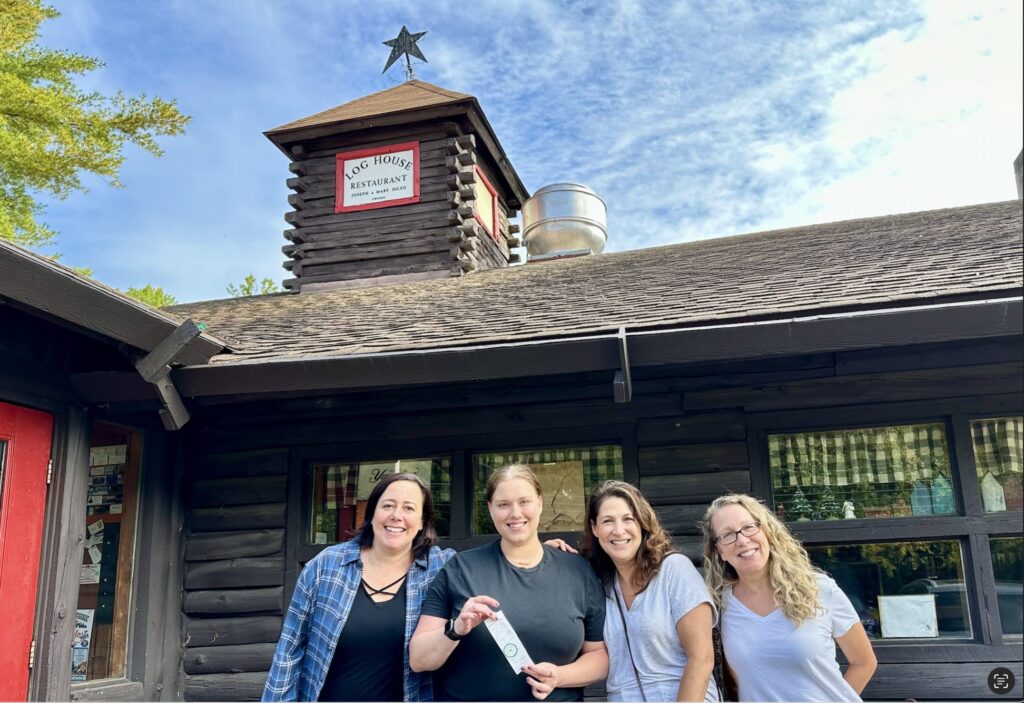 Three women holding a receipt that has a $1,000 tip on it.